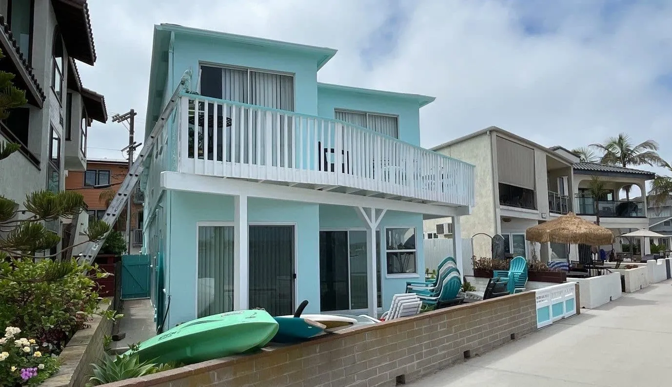 Teal beach duplex with white railings after painting