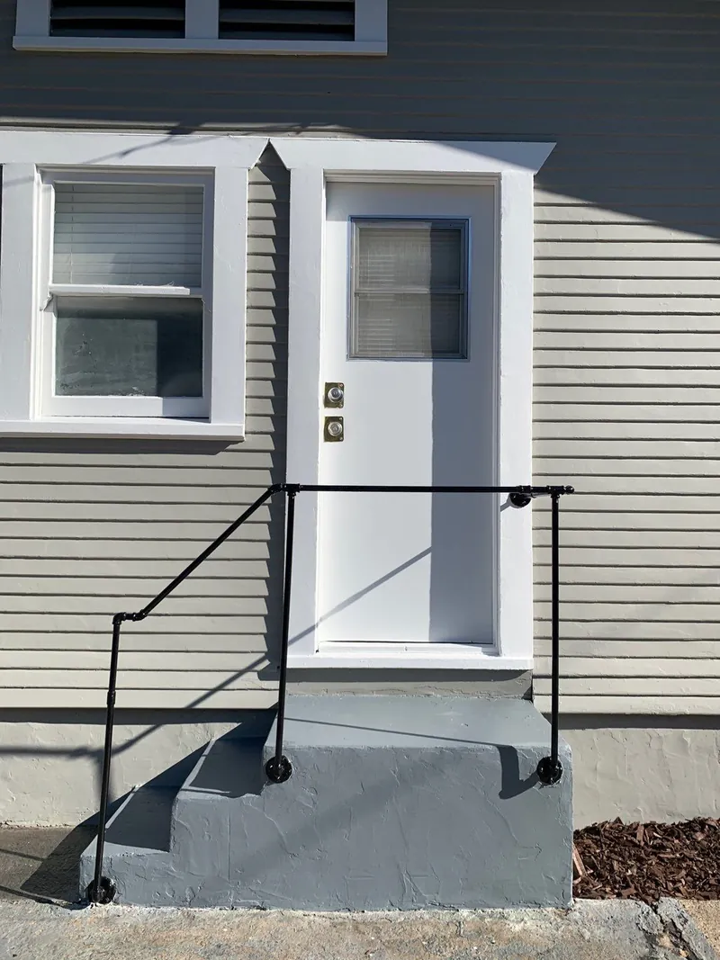Painted side door, trim and steps on a gray bungalow