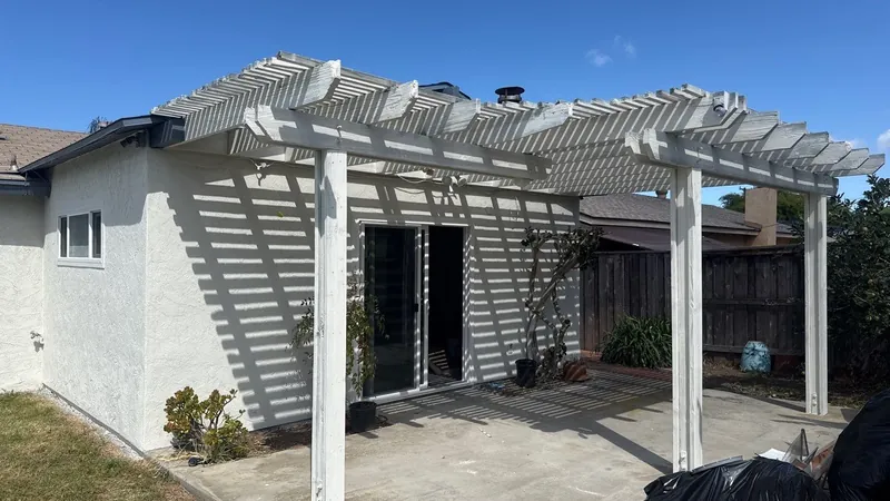 Patio pergola painted white against the refinished house
