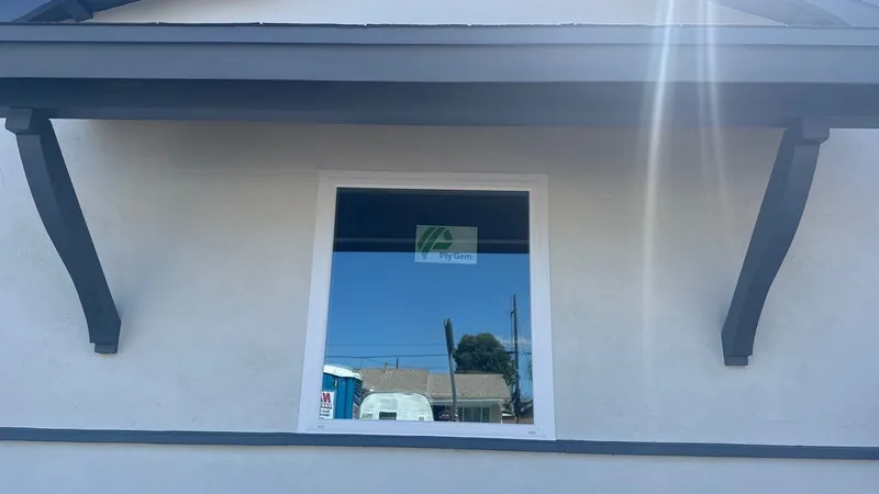 New window under charcoal brackets and fascia on white stucco