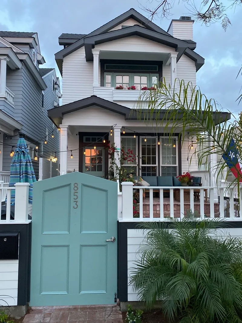 Narrow Coronado home with a teal gate and white trim