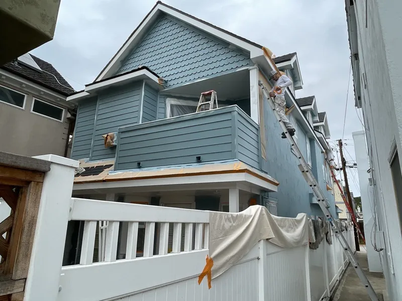 Blue-gray siding and white trim on the side of a narrow Coronado home