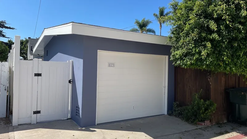 Detached garage painted navy with a white garage door