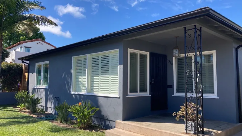 Navy stucco cottage with white shutters and a black front door