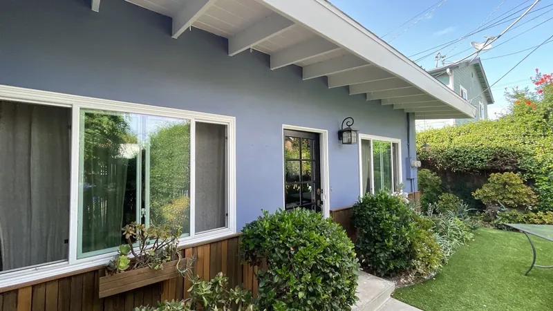 Side of a navy stucco home with new white window trim