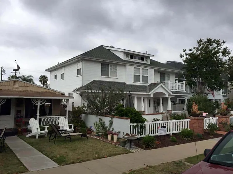 All-white craftsman exterior with a white picket fence in Coronado