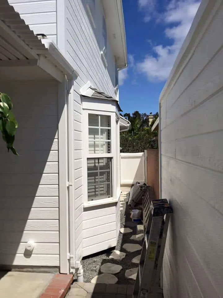 Narrow side yard with freshly painted white siding