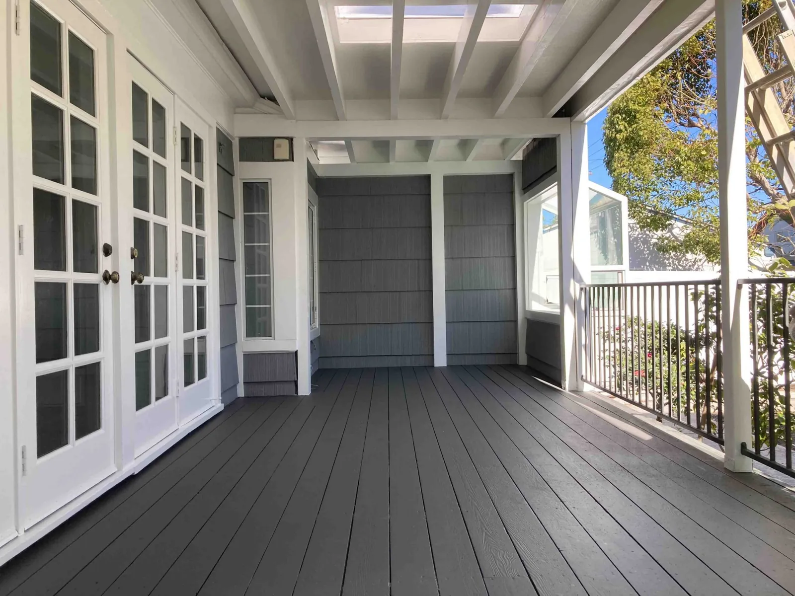 Covered porch with new deck boards, white trim and gray siding