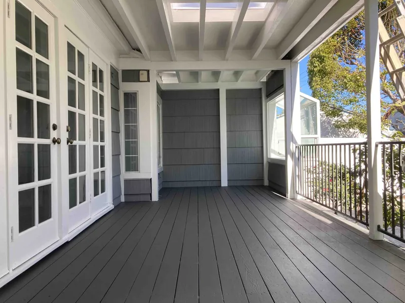 Covered porch with new deck boards, white trim and gray siding