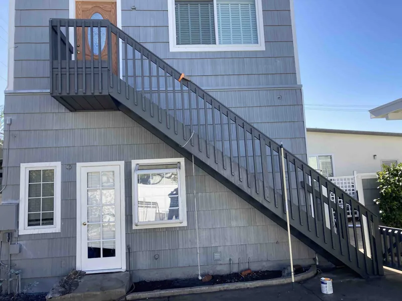New exterior staircase and gray shingle siding after restoration