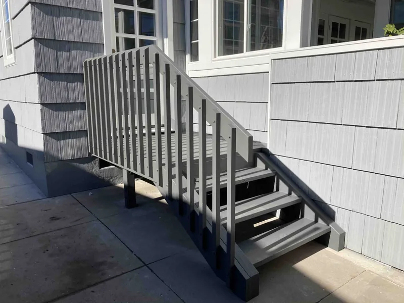 Rebuilt exterior stairs painted charcoal next to fresh gray siding