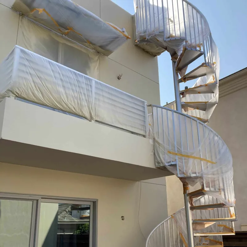 Balcony and spiral staircase masked during exterior painting