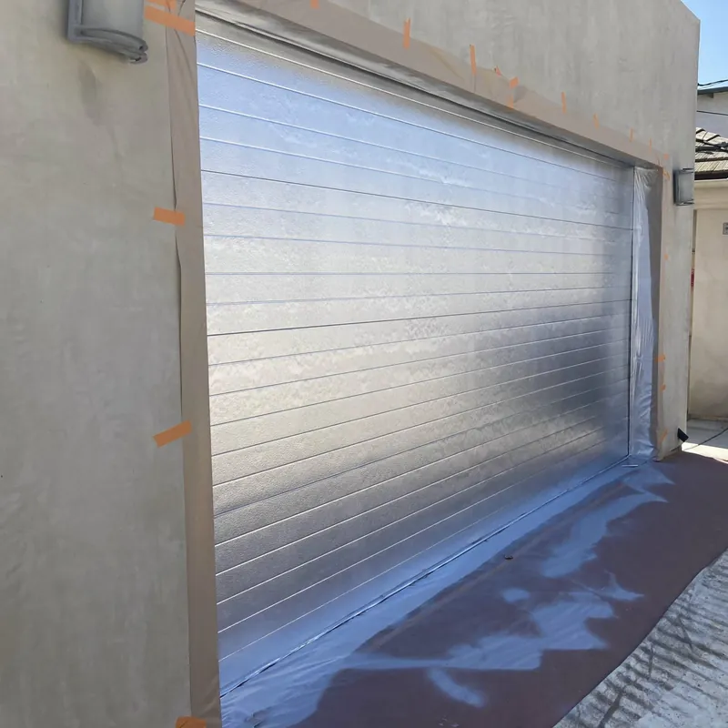 Garage door masked while smooth stucco walls are painted