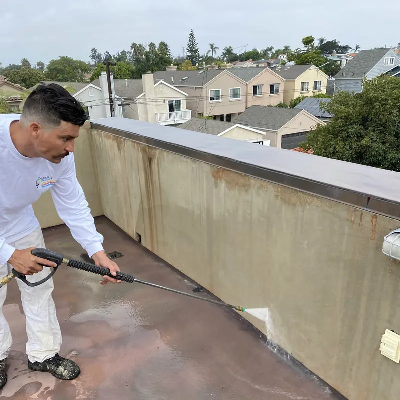 Painter pressure washing a rooftop deck wall in Coronado