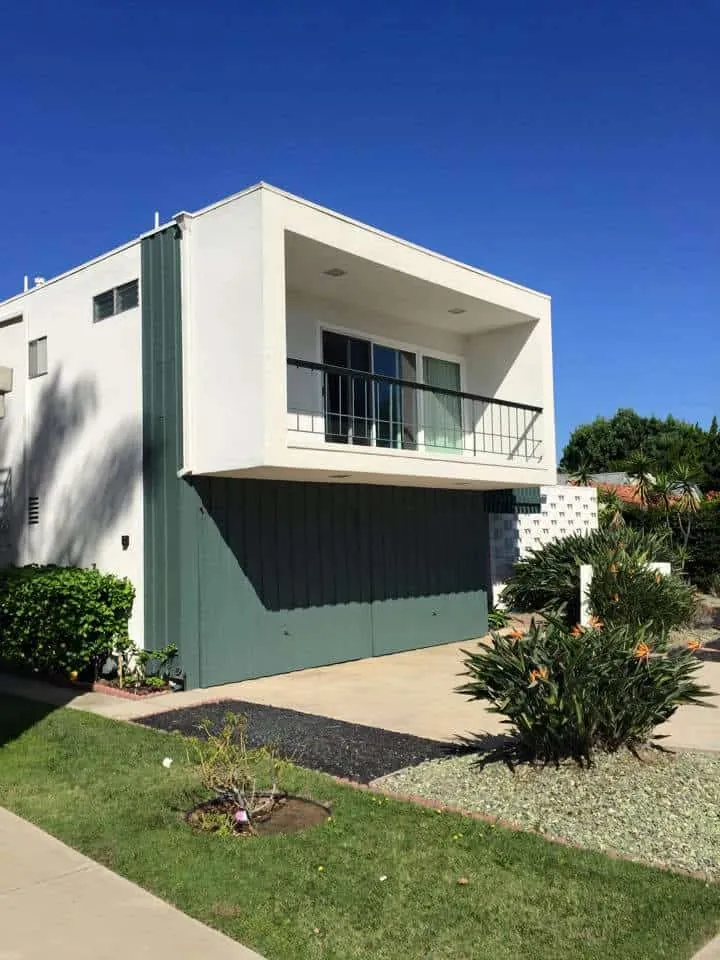 Mid-century home exterior with sage green siding and white stucco