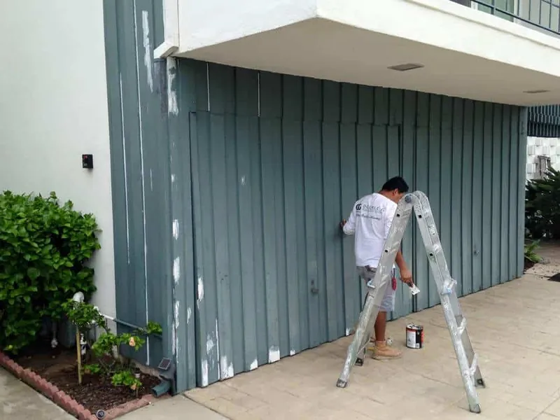 Painter on a ladder painting board-and-batten siding