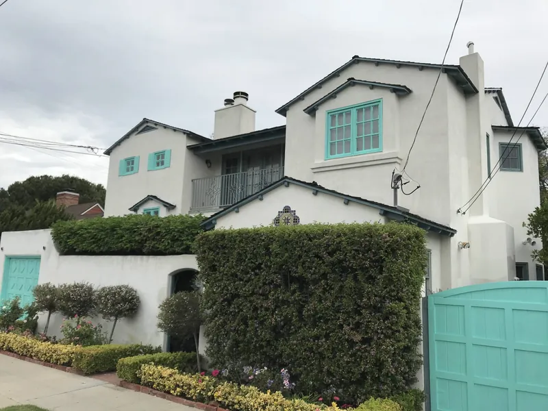 White stucco home with teal shutters and gate after painting