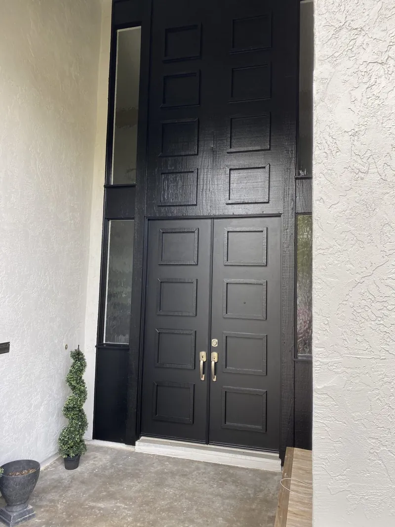 Black double front door painted against white stucco