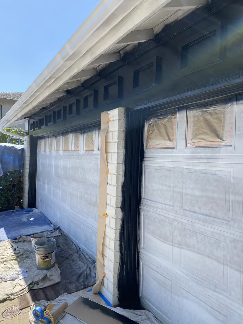 Black fascia and trim being painted over white garage doors