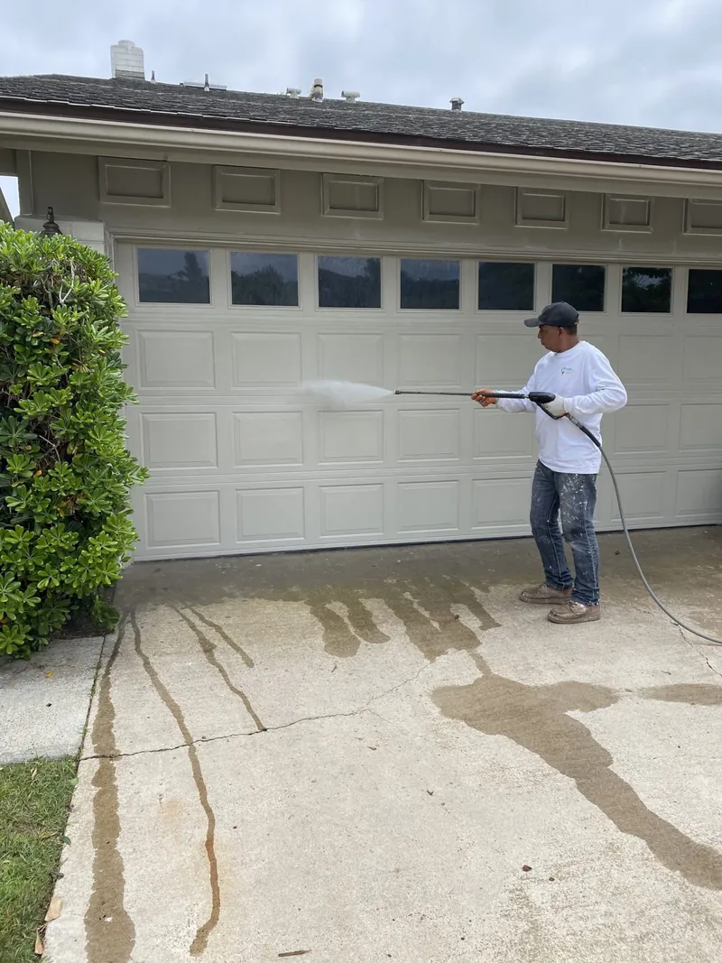 Painter pressure washing the garage and driveway before exterior painting