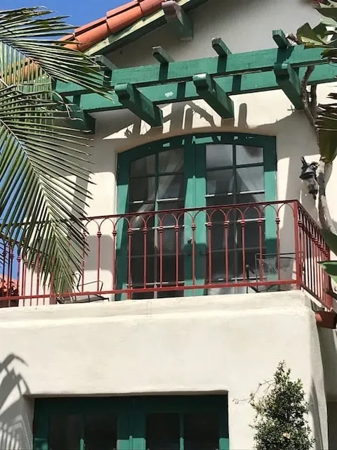 Balcony with green trellis and red iron railing after painting