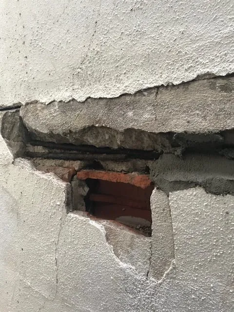 Cracked and broken stucco exposing brick before repair