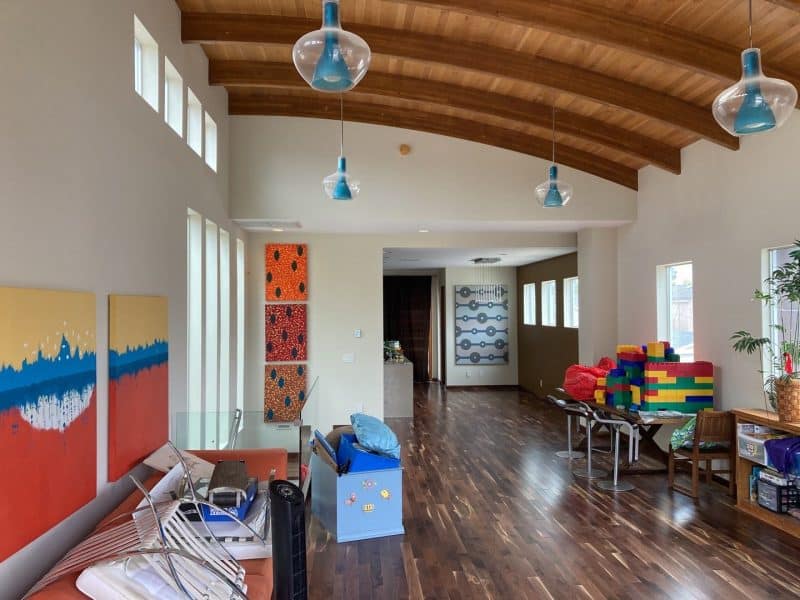 A spacious interior with wooden beams, colorful artwork, and toys in a play area.