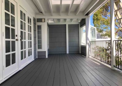 Empty covered porch with gray flooring and white doors