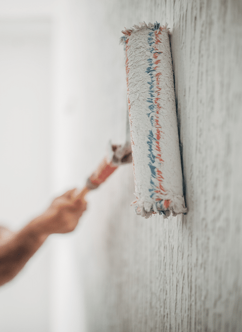 A person using a paint roller to apply paint to a wall.