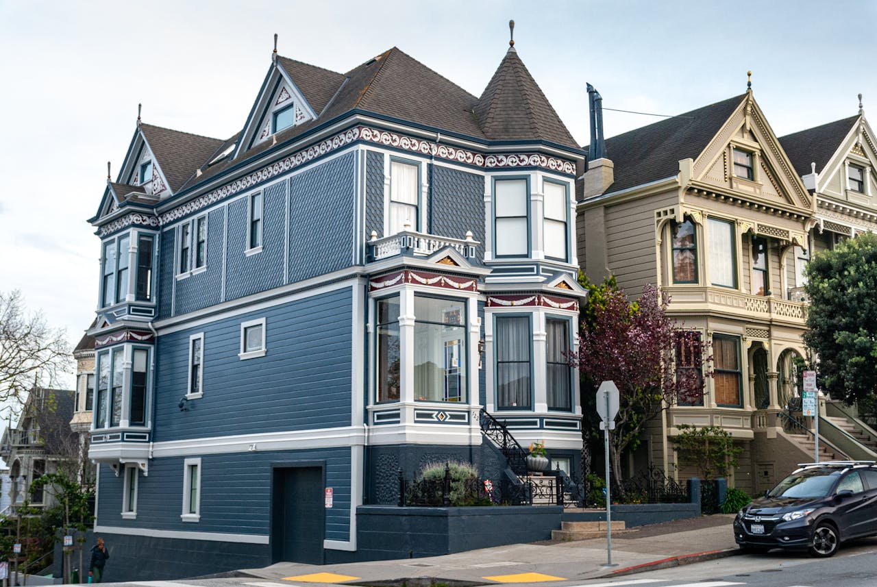 Blue Victorian-style home freshly painted on a sloped street, illustrating how to protect exterior paint from rain and maintain a durable finish.