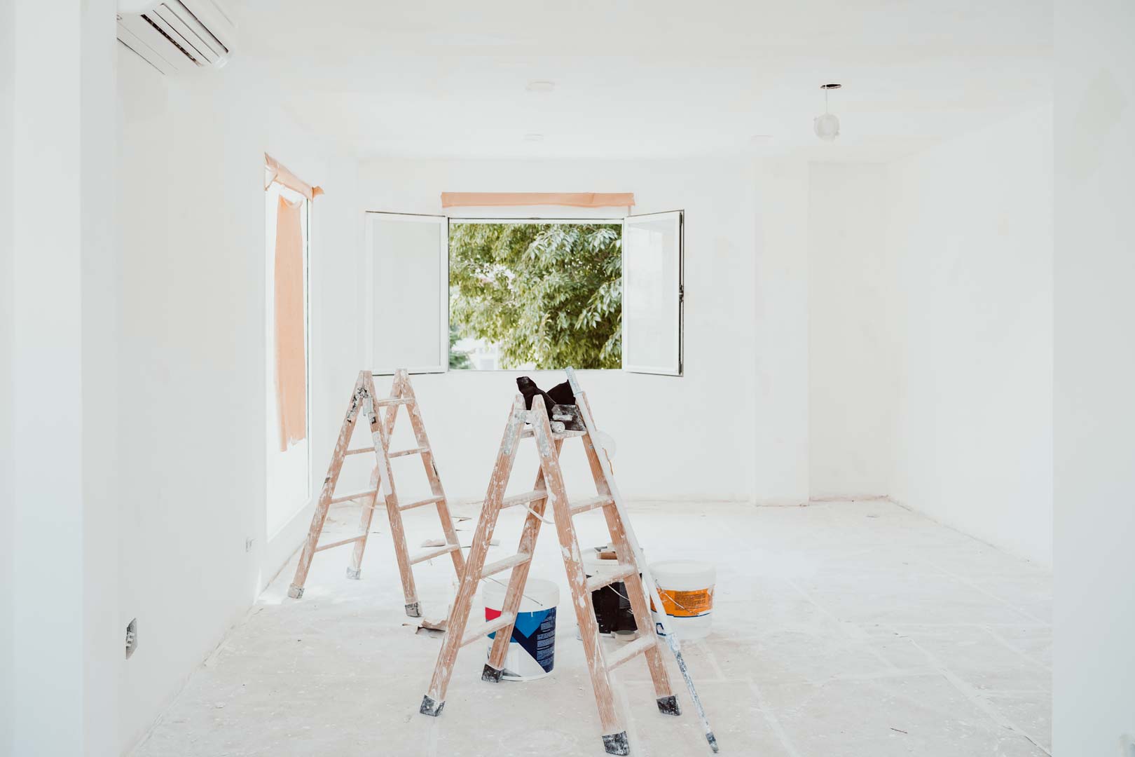 Freshly painted bright white room with ladders, paint cans, and open windows prepared by professional interior painters in San Diego.