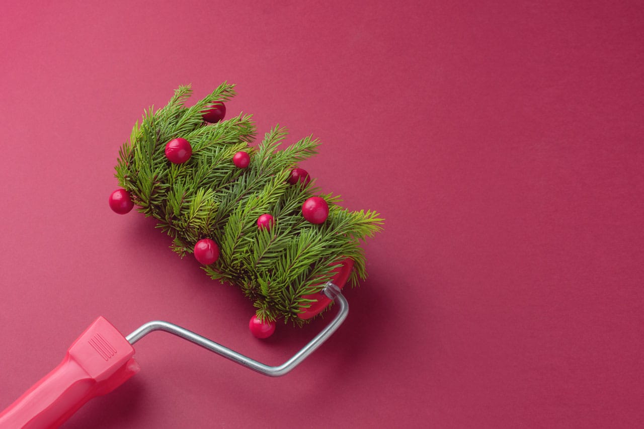 A paint roller decorated with evergreen branches and red ornaments, symbolizing Seasonal Accent Walls Painting San Diego by San Diego interior painters for the holidays.