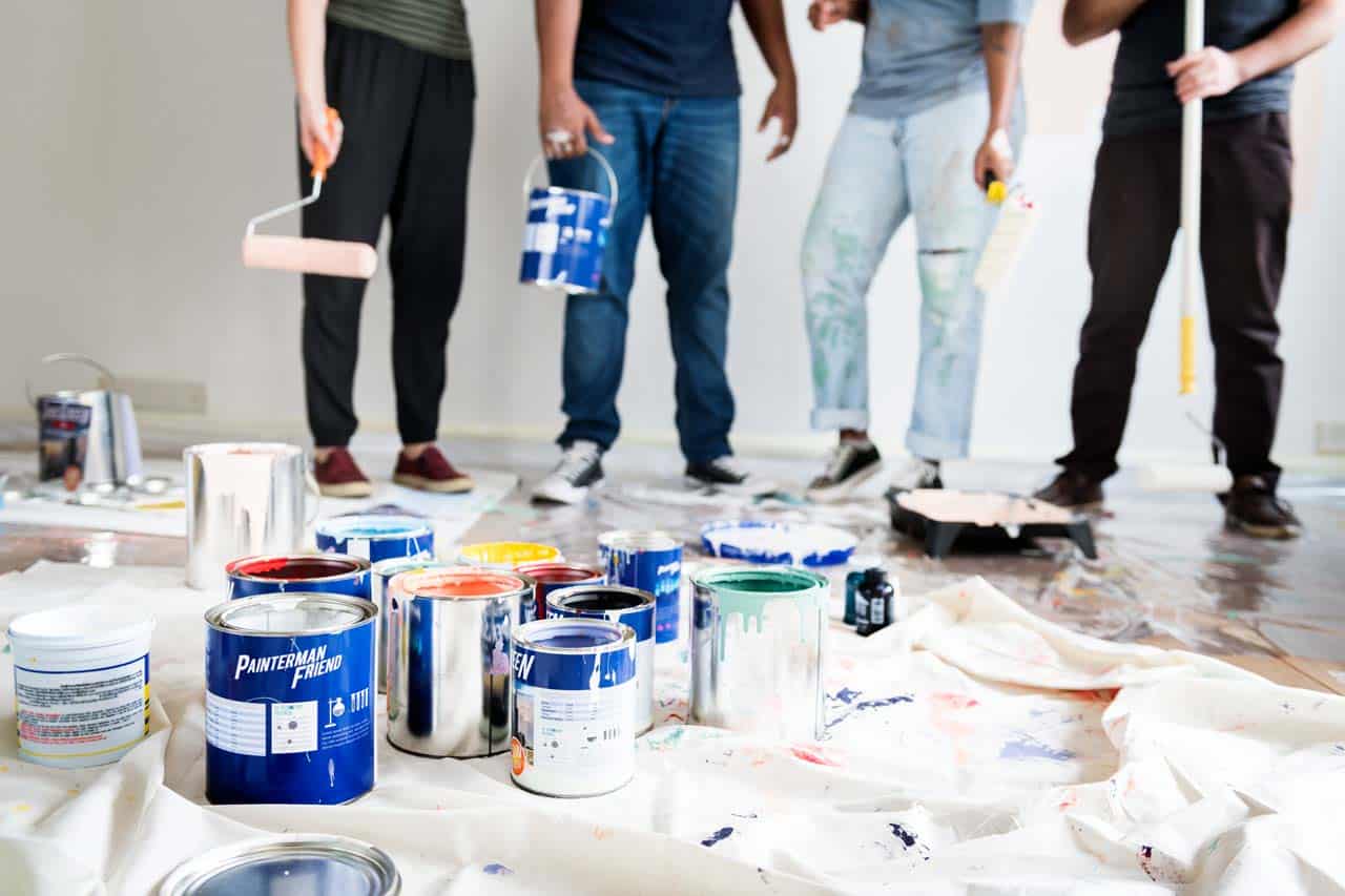 House painting projects San Diego with homeowners using rollers and paint cans to refresh interior walls for an affordable makeover.