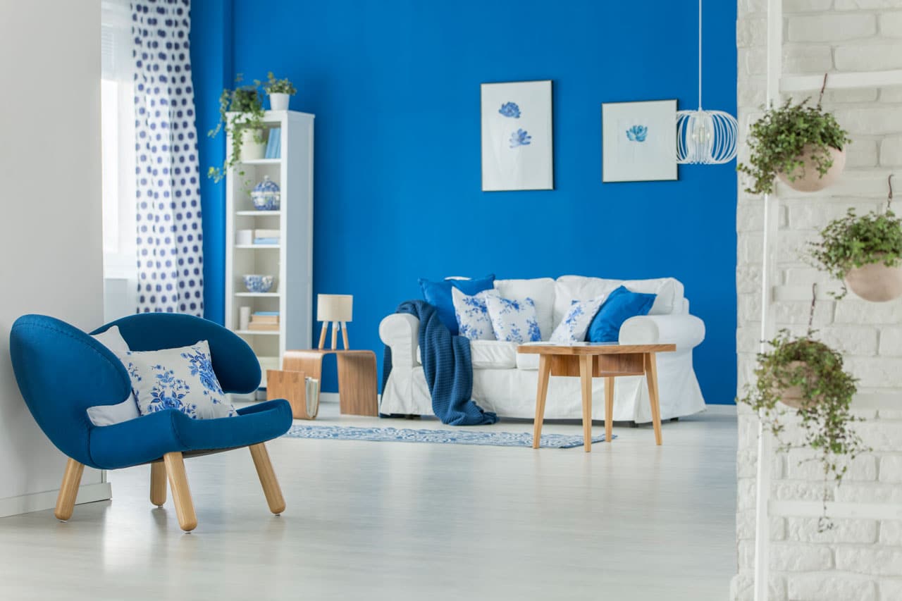 San Diego Interior Painters New Year Trending Color inspiration showing a modern living room with bold blue walls, fresh white furniture, and updated interior paint design.
